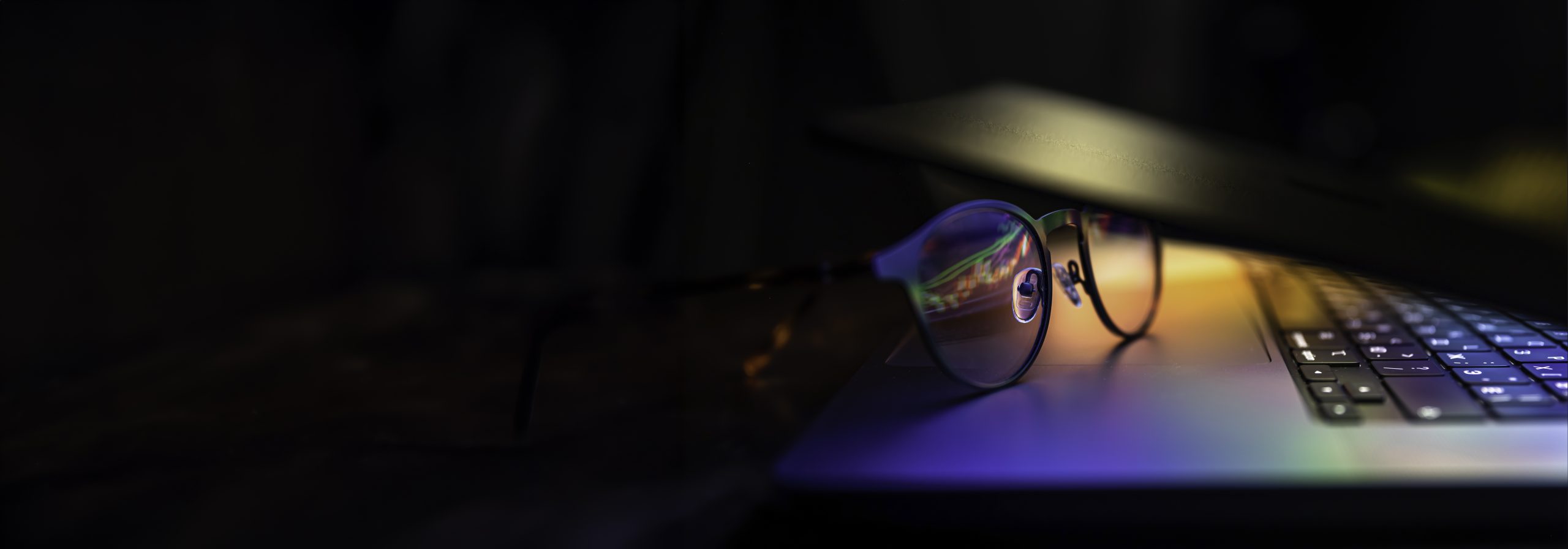 /wp-content/uploads/2025/05/las-gafas-se-encuentran-en-la-computadora-portatil-reflejando-la-luz-de-la-pantalla-en-la-oscuridad-scaled.jpg